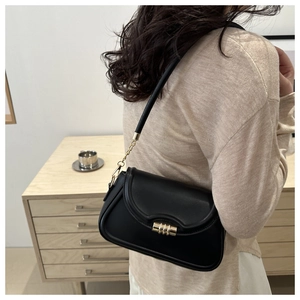 Detail view of black vintage underarm bag with gold triple-ring clasp and chain strap