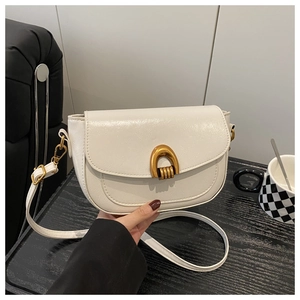 Detailed view of vintage cream saddle bag featuring a large gold U-shaped metal buckle