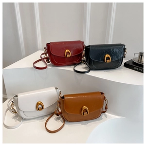 Detail of four retro saddle bags with gold U-shaped hardware displayed on white steps