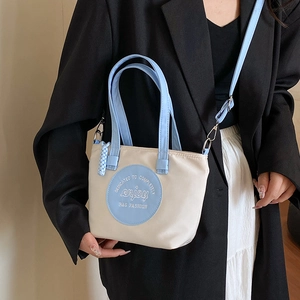 Sac à main minimaliste beige et bleu clair pour femme présenté dans un cadre lifestyle