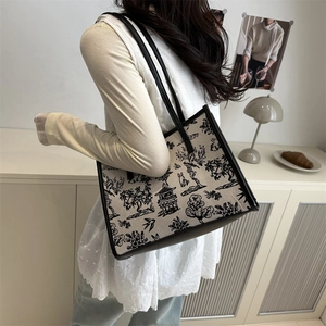 Chic canvas tote bag with landscape print and black leather straps on a model