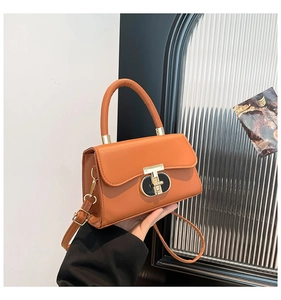 Detail of bright orange faux leather bag with golden T-bar metal clasp and top handle