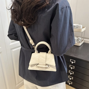Minimalist white textured leather crossbody bag with buckle closure and adjustable strap