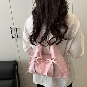 Pink underarm bag with white bows and silver zippers shown on model back view