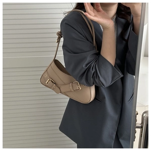 Detail of camel leather underarm bag with metal buckles and vintage biker style straps