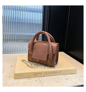 Close-up of brown crocodile embossed leather mini bag with silver chain and dual handles