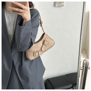 Mirror selfie showing a tan saddle-style underarm bag with gold buckles on a grey suit