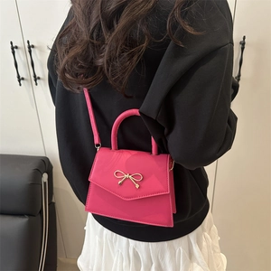 Chic magenta glossy mini crossbody bag with golden bow and top handle for women