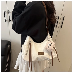 Detail of white canvas tote with brown leather straps and cute plush bear charm
