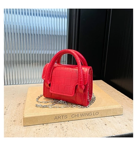 Detailed close-up of red crocodile-embossed mini bag with silver chain strap and flap cover