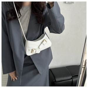 Detail shot of white leather saddle bag showing iconic metal buckles and curved design