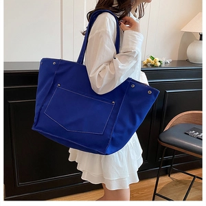 Close-up of royal blue canvas tote bag featuring white contrast stitching and large pocket