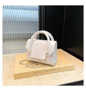 Detail view of the white mini handbag featuring crocodile embossing and silver metal chain