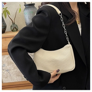 Detail of off-white crescent underarm bag with woven texture and silver chain strap
