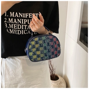 Gros plan d'un sac à main en tweed à carreaux colorés avec franges et poignée en cuir