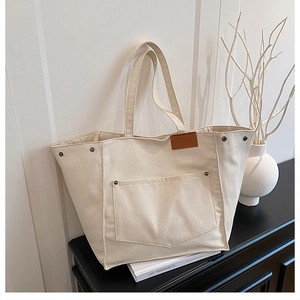 Detail of canvas tote bag with brown leather label and metal rivets on black cabinet