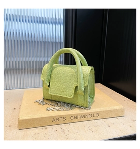 Detail of lime green faux leather handbag with crocodile pattern and silver chain strap
