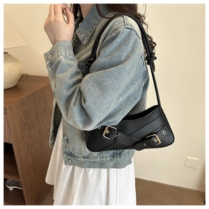 Detail view of the black retro belt-style shoulder bag with metallic buckle hardware