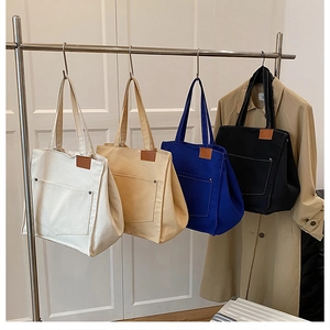 Détail de sacs fourre-tout en toile blanc, beige, bleu, noir avec patch en cuir