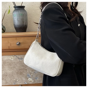 Detail of cream woven crescent bag with silver chunky chain strap on a model