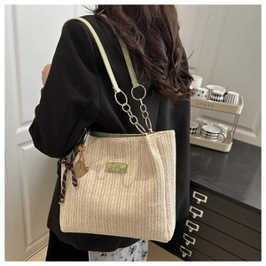 Detail of woven tote bag featuring green leather trim and tennis racket charm accessory
