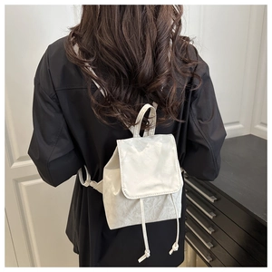 Détail du mini sac à dos plissé beige avec cordon de serrage porté par un mannequin