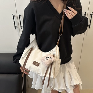 Minimalist beige nylon hobo shoulder bag with brown adjustable strap and plush charm
