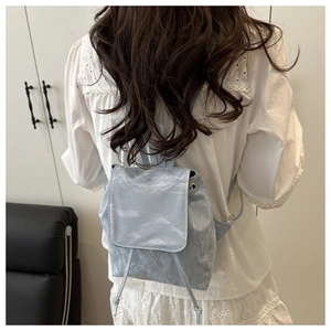 Détail du mini sac à dos bleu clair avec texture plissée porté par un modèle
