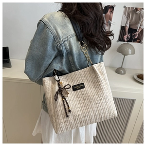 Détail du sac cabas tissé avec texture en V, bandoulière en chaîne et nœud décoratif