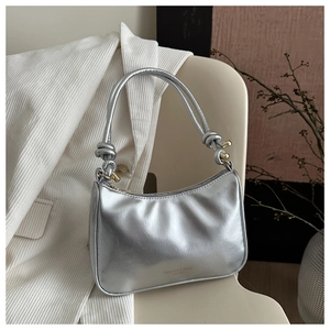 Detail of silver metallic hobo bag featuring knotted rope straps and gold hardware