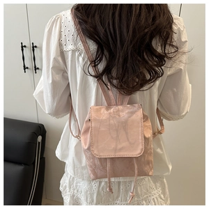 Détail d'un mini sac à dos rose clair avec fermeture à cordon et texture plissée élégante