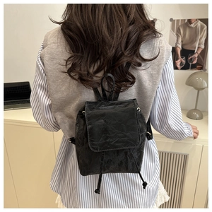Vue arrière d'un sac à dos vintage noir avec texture froissée porté par un mannequin