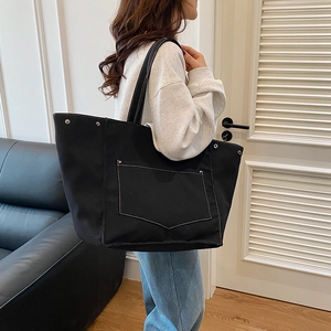 Minimalist black canvas tote bag with contrast white stitching and large front pocket