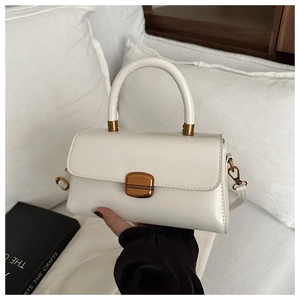 Detail of white minimalist handbag with gold rectangular buckle and sleek top handle