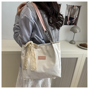 Detail of cream tote bag with pink leather chain strap and lace bow charm