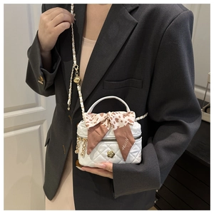 Detail of white quilted mini bag with gold camellia clasp and leopard print silk scarf