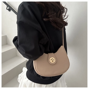 Detailed view of beige crescent bag with gold twist lock on a minimalist model shoulder