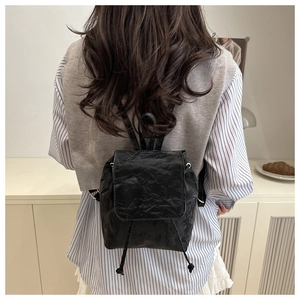 Détail d'un petit sac à dos noir avec texture plissée porté par un mannequin