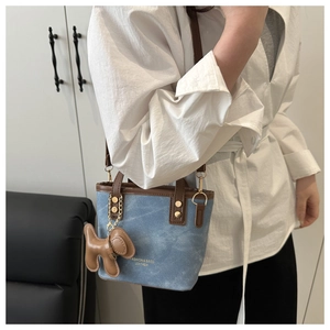 Detail of blue denim canvas tote bag with brown leather trim and cute puppy charm