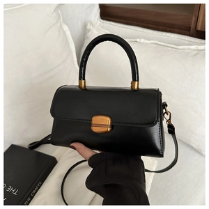Detail of black crossbody bag featuring a golden metallic buckle and premium glossy finish