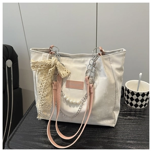 Detail of cream tote bag featuring pink straps, chunky metal chain and pearl charms