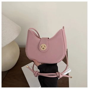 Detailed view of pink crescent bag with golden cylinder lock and knotted shoulder strap