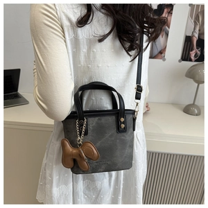 Dark gray crossbody bag with a cute dog charm shown on a model in a modern office setting