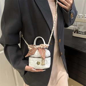 White quilted mini bucket bag with gold floral accents and silk scarf detail on model
