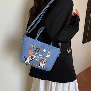 Blue denim crossbody bucket bag with vintage cat illustration and adjustable shoulder strap
