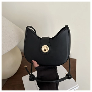 Detail of black crescent shoulder bag featuring golden metal twist lock and knotted strap