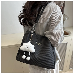 Close-up of large black tote bag featuring chain strap and cute cloud plush charm