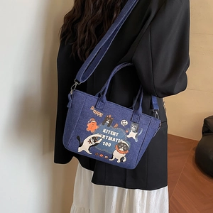 Navy canvas tote bag with cartoon cat prints and detachable strap worn by model