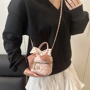 Pink quilted bucket bag with leopard bow and camellia charm in crossbody view