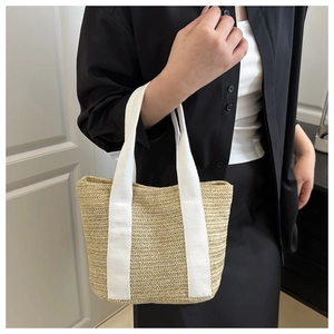 Detail of woven straw handbag featuring sturdy white canvas straps and natural texture
